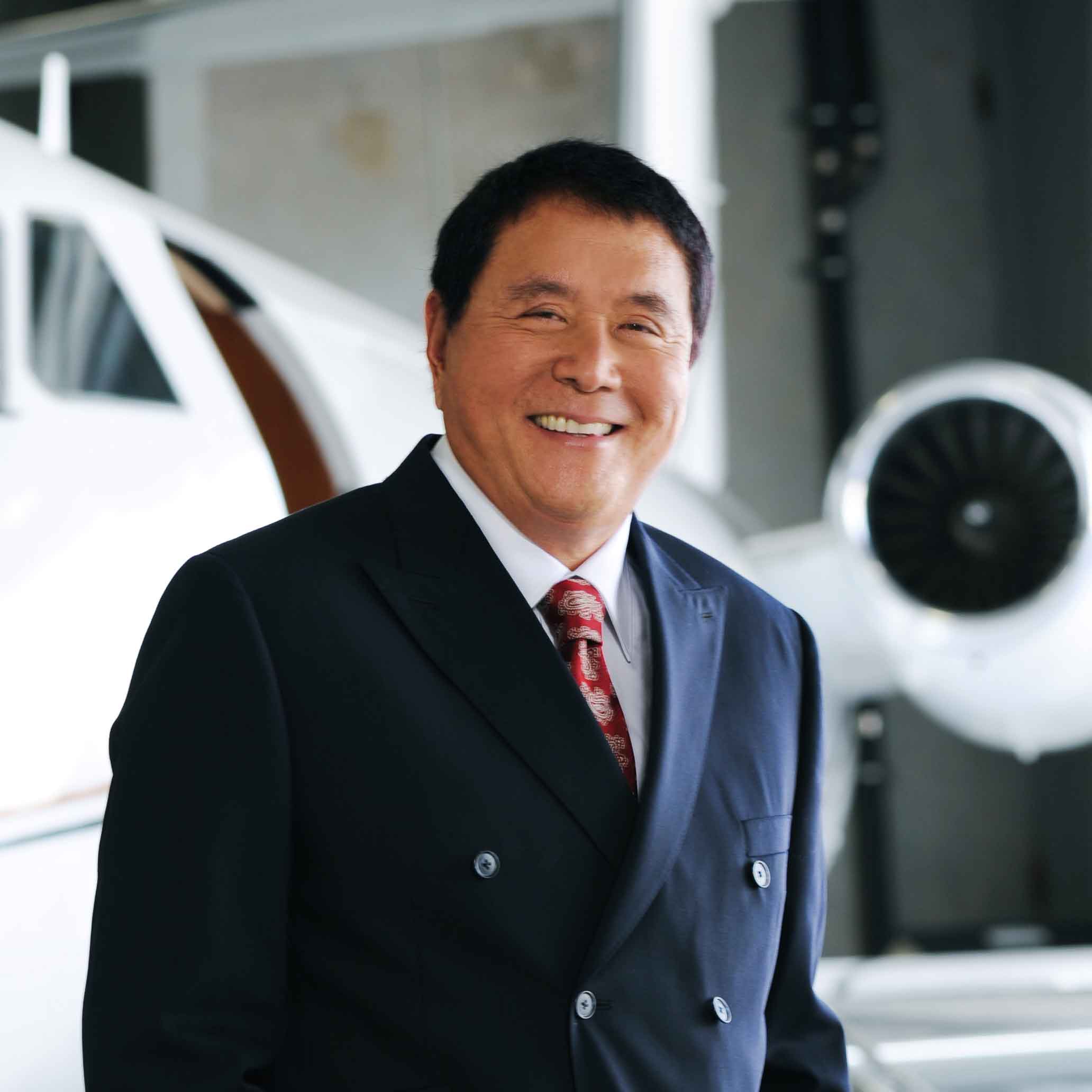 Robert Kiyosaki standing by a private jet in an airplane hanger